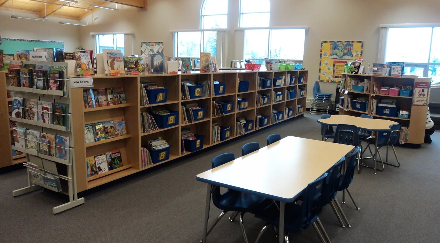 a photo of the Learning Commons showing rows of books and tables in front of large windows